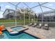 Backyard view of a refreshing screened-in pool and spa, surrounded by lounge chairs and lush landscaping at 9020 Stinger Dr, Davenport, FL 33896
