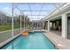 Sparkling screened-in pool and patio area with outdoor seating, a grill, and an inflatable tiger float at 9020 Stinger Dr, Davenport, FL 33896