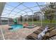 Sparkling screened-in pool and spa area with outdoor lounge chairs and blue accents at 9020 Stinger Dr, Davenport, FL 33896
