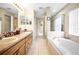 Bathroom featuring double vanity, a soaking tub, and neutral tile flooring at 952 Chamberlin Trl, St Cloud, FL 34772