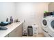 Bright laundry room features a sink, white countertop, gray cabinets, and modern white washer and dryer at 10364 Shive Island Ct, Orlando, FL 32827