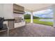 Covered outdoor kitchen with stainless steel appliances and a brick patio overlooking the serene backyard at 10364 Shive Island Ct, Orlando, FL 32827