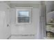 A clean and bright white tiled bathroom with a window, shower, and storage shelving at 11730 Kennington Ct, Orlando, FL 32824