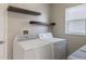 Bright laundry room with floating shelves above the white washer and dryer, and a natural light window at 12303 Bohannon Blvd, Orlando, FL 32824