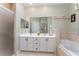 Bathroom featuring double sinks, white cabinetry, large mirror, shower, and a soaking tub at 1321 Artisan E Ave, Celebration, FL 34747
