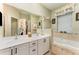 Bright bathroom with a double vanity, a large mirror, and a soaking tub under the window at 1321 Artisan E Ave, Celebration, FL 34747