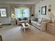 Bright living room featuring neutral carpeting, a large window with stylish curtains, and classic furniture at 1410 Sanchez Ct, Lady Lake, FL 32159