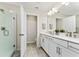 A bright bathroom featuring a double vanity, open doorway, and a glass-enclosed shower at 14416 Orchid Island Dr, Orlando, FL 32827