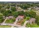 Aerial view displaying houses with lush lawns, mature trees, and a glimpse of a distant lake at 14610 Wishing Wind Way, Clermont, FL 34711