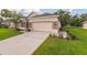 Home's two-car garage with a driveway, stone accents, and verdant lawn at 1746 Golfview Dr, Kissimmee, FL 34746