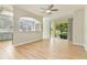 Open-concept living room with wood floors, ceiling fan, and view into kitchen and outside at 1746 Golfview Dr, Kissimmee, FL 34746