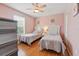 Charming pink bedroom with two twin beds, wood floors, and a ceiling fan at 203 La Mirage St, Davenport, FL 33897