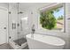 Modern bathroom features a soaking tub next to a large window and a glass enclosed shower at 2421 Deermeadow Dr, Apopka, FL 32703