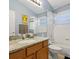 Bathroom with granite countertop, wood vanity, bathtub with shower, and blue walls at 2567 Oneida Loop, Kissimmee, FL 34747