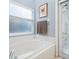 Bright bathroom featuring a soaking tub, tile surround, and a window with blinds at 2567 Oneida Loop, Kissimmee, FL 34747