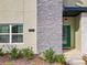 Close-up of modern townhome entrance with green door, stacked stone, and manicured landscaping at 2970 Protagonist St, Kissimmee, FL 34746