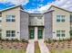 Close-up of a modern townhome's front facade with stacked stone detail and vibrant green doors at 2970 Protagonist St, Kissimmee, FL 34746