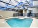 Screened-in pool and hot tub with lounge chair, surrounded by black safety fence, with an open patio space in the background at 2970 Protagonist St, Kissimmee, FL 34746