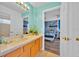 Well-lit bathroom with wood cabinets, large mirror, and a view into a bedroom at 303 Plumoso Loop, Davenport, FL 33897
