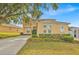 Charming two-story peach home featuring an arched entry, manicured lawn, and a lengthy driveway at 303 Plumoso Loop, Davenport, FL 33897