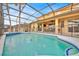 Screened-in pool area with a dining set, pool safety fence and views of the home at 303 Plumoso Loop, Davenport, FL 33897