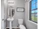 Powder room with white toilet and pedestal sink, wood-look flooring, gray walls, and vanity light at 320 Southern Winds Blvd, Deland, FL 32720
