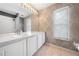 A well-lit bathroom showcases double sinks, a large mirror, decorative wallpaper, and a walk-in shower at 3203 Herons Point Cir, Kissimmee, FL 34741