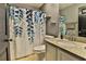 Bathroom features a vanity with granite countertop, toilet, and shower with blue leaf curtain at 330 Chiquita Ct, Kissimmee, FL 34758