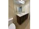 Bathroom featuring double sinks, vanity with dark wood cabinetry, large mirror, and neutral walls at 4855 Coral Castle Dr, Kissimmee, FL 34746