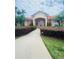 Clubhouse featuring stucco walls, terracotta roof, landscaped garden beds, and a paved walkway at 4855 Coral Castle Dr, Kissimmee, FL 34746