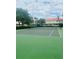 Tennis court with lush greenery and well-maintained surface, surrounded by trees and community buildings at 4855 Coral Castle Dr, Kissimmee, FL 34746