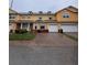 Inviting yellow townhome with a brick paved driveway leading to a single-car garage for convenient parking at 4981 Alita Ter, St Cloud, FL 34769