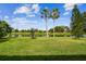 A lush backyard with a serene pond view and swaying palm trees under a blue sky at 517 Milano Rd, Poinciana, FL 34759