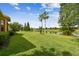 Expansive backyard showcasing well-manicured lawn and tranquil pond view with palm trees at 517 Milano Rd, Poinciana, FL 34759