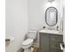 Powder bath featuring a gray vanity, oval mirror, and toilet at 517 Milano Rd, Poinciana, FL 34759