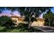 Inviting home with a well-manicured lawn, mature trees, and a paver driveway leading to the garage at 517 Milano Rd, Poinciana, FL 34759
