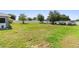 Expansive grassy backyard featuring mature shade trees, a white picket fence and room for outdoor activities at 6006 Country Walk Ln, Winter Haven, FL 33880