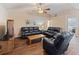 Inviting living room features wood floors, a ceiling fan, and comfortable black leather furniture at 6006 Country Walk Ln, Winter Haven, FL 33880