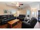 Bright living room with wood flooring features black leather sofas and vaulted ceiling with fan at 6006 Country Walk Ln, Winter Haven, FL 33880