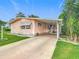 Charming pink home featuring a covered driveway, well-maintained lawn, and mature landscaping at 6044 Grand Oaks Se Dr, Winter Haven, FL 33884