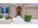 Inviting front entrance with a pathway flanked by decorative stone and lush greenery, enhancing curb appeal at 647 Washington Way, Haines City, FL 33844