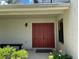 Warm home entrance with a beautiful red double-door and decorative foliage around the home at 7200 Green Pine Ct, Orlando, FL 32819