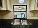 Close up of a stainless steel kitchen sink with black countertops and window view of the outdoor pool at 7200 Green Pine Ct, Orlando, FL 32819