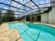 Backyard view of a screened pool and spa with clear blue water, set in a private, tropical landscape at 7200 Green Pine Ct, Orlando, FL 32819
