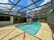 Backyard view of a screened pool and spa with clear blue water, set in a private, tropical landscape at 7200 Green Pine Ct, Orlando, FL 32819