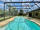 Backyard view of a screened pool and spa with clear blue water, set in a private, tropical landscape at 7200 Green Pine Ct, Orlando, FL 32819