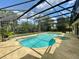 Backyard view of a screened pool and spa with clear blue water, set in a private, tropical landscape at 7200 Green Pine Ct, Orlando, FL 32819