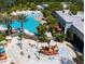 Aerial view of a resort-style community pool, splash pad, and lounging area with lush greenery at 726 Longboat, Davenport, FL 33896
