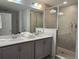 Modern bathroom with double sink vanity, stone countertops, large mirror, and tiled walk-in shower at 726 Longboat, Davenport, FL 33896