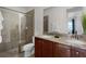 Modern bathroom featuring double sinks, granite countertops, wooden cabinets, and a glass-enclosed shower at 7527 Marker Ave, Kissimmee, FL 34747